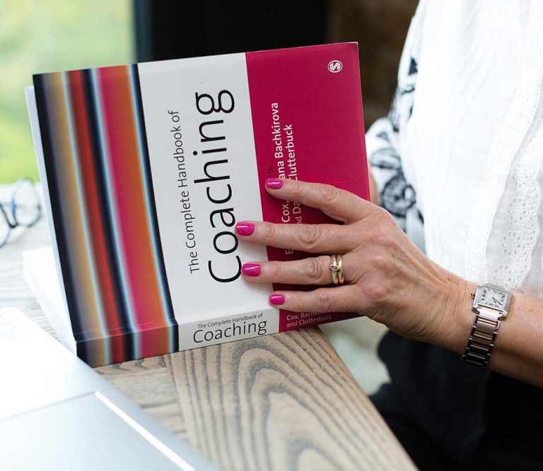 A person reading the complete handbook of coaching book